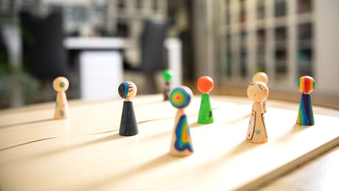 Bunt bemalte Holzfiguren symbolisieren Vielfalt und individuelle Wege in der Beratung